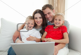 Jolly family using a computer sitting on sofa