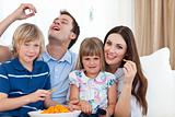 Young family eating crisps while watching TV 