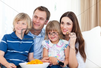 Family watching television and eating chips