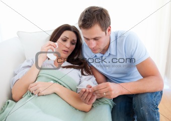 Concerned man taking his sick wife's temperature