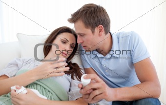 Husband carring his sick wife and giving to her pills
