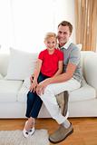 Blond little girl sitting on sofa with her father