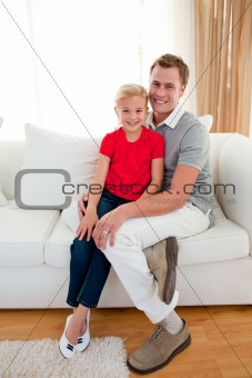 Blond little girl sitting on sofa with her father