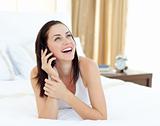 Radiant woman on phone lying on her bed 