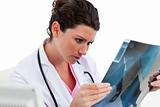 Concentrated female doctor looking at X-ray in his office