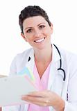 Brunette doctor reading paper and holding a stethoscope