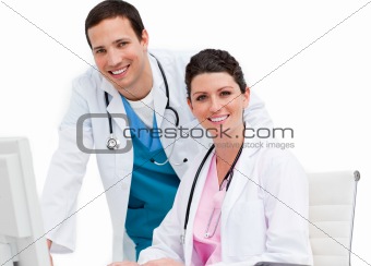 Two smiling doctors working at a computer