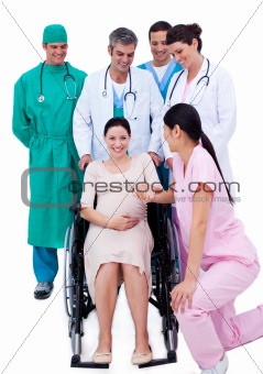 Pretty pregnant woman sitting on wheelchair and a medical team