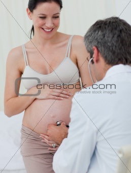 Smiling pregnant woman examined by her gynecologist