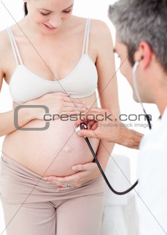 Smiling pregnant woman examined by her gynecologist