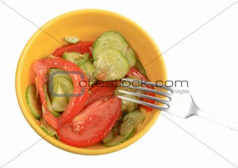 Salad from fresh cucumbers and tomatoes on a yellow plate