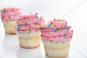shot of Three cupcakes with sprinkles in a line