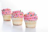 shot of Three cupcakes with sprinkles in a line isolated on white