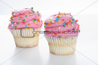 shot of Two pink gourmet cupcake isolated on white