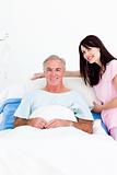 Caring nurse adjusting pillows for a senior patient