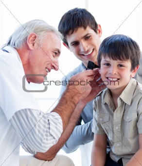 Senior doctor examining a little boy's ears