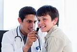 Concentrated doctor examining little boy's ears