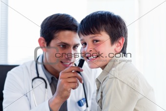 Concentrated doctor examining little boy's ears