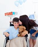 Cheerful little boy sitting on wheelchair and his mother