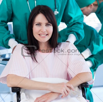 Ethnic surgeon carrying a female patient on a wheelchair