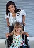 Portrait of a little girl on a wheelchair and a young doctor