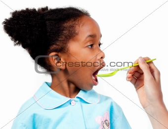 Close-up of a cute little girl taking medicine 