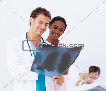Pediatrician and nurse examining an x-ray and a little patient i