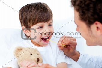 Positive doctor taking little boy's temperature
