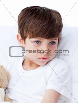 Sick little boy lying in a hospital bed 