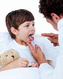 Male doctor checking little boy's throat 