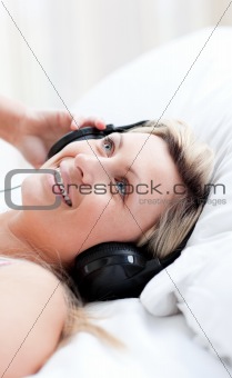 Charming woman with headphones on lying on a bed