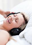 Enthusiastic woman with headphones on lying on a bed