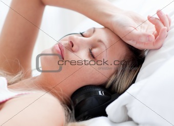 Cute woman with headphones on lying on a bed
