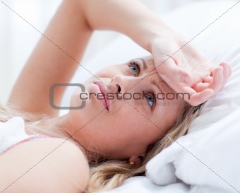 Upset woman having a migraine lying on a bed 