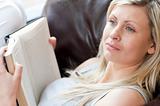 Beautiful woman reading a book sitting on a sofa