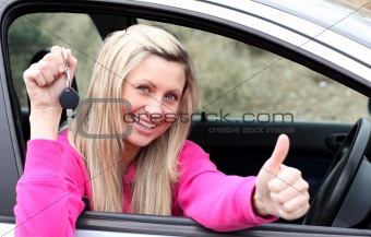 Jolly female driver showing a key after bying a new car 