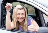 Charming female driver showing a key after bying a new car 