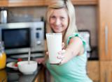 Happy woman holding a glass of milk while having an healthy brea