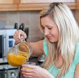 Smiling woman drinking orange juice in a kitchen