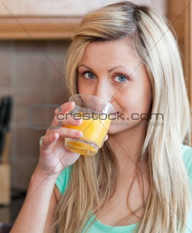 Charming woman drinking orange juice  in a kitchen