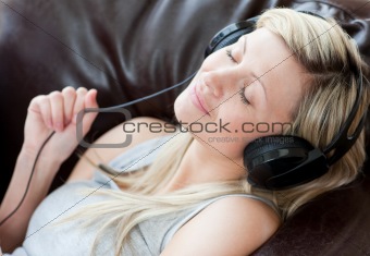 Relaxed woman with headphones on lying on a sofa