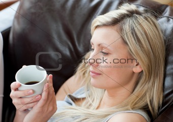 Relaxed woman drinking coffee sitting on a sofa in a living-room