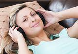 Smiling woman with headphones on lying on a sofa 