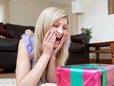 Surprised woman opening gifts lying on the floor 