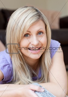 Blond woman watching TV lying on the floor 
