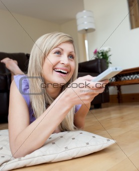 Laughing woman watching TV lying on the floor