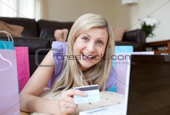 Laughing woman shopping online lying on the floor