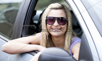 Jolly female driver wearing sunglasses sitting in her car 