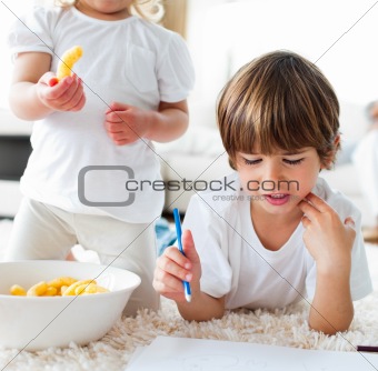 Close-up of children eating chips and drawing 