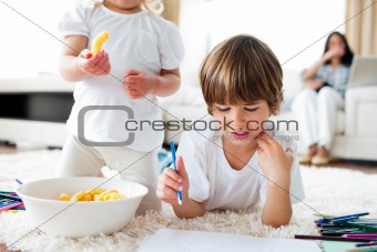 Close-up of siblings eating chips and drawing